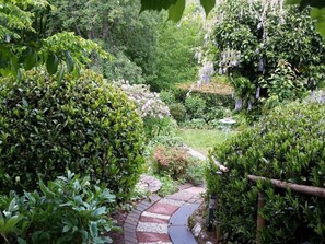 Un camí al jardí envoltat de vegetació exuberant i plantes en flor.