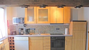 A compact kitchen with wooden cabinets, a microwave, a coffee maker, and a dishwasher. - Santa Maria by Interhome (Nettersheim)