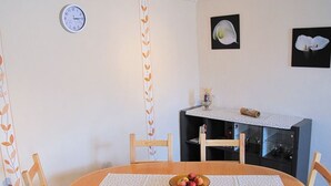 A dining area with a round wooden table, four chairs, a clock on the wall, and a small cabinet with a decorative cloth. - Santa Maria by Interhome (Nettersheim)