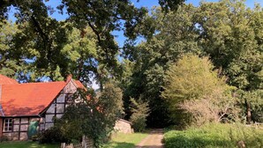 A rural pathway leading to a traditional half-timbered house with a red roof, surrounded by dense greenery and trees. - Schönes Ferienhaus in Brochterbeck mit Garten by Interhome (Tecklenburg)