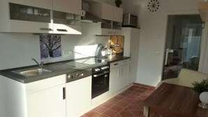 A modern kitchen with white cabinets, a stainless steel sink, and a tiled floor. - Schönes Ferienhaus in Brochterbeck mit Garten by Interhome (Tecklenburg)