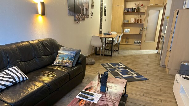 Una sala de estar con un sofá de cuero, una mesa de centro con un modelo de la ciudad y una zona de comedor con sillas y una mesa.