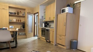 Un espacio habitable compacto con comedor, kitchenette y una pequeña zona de estar.