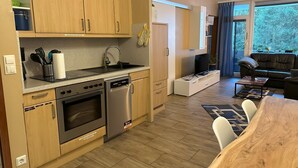 Una cocina moderna con electrodomésticos de acero inoxidable, armarios de madera y un comedor con mesa y sillas de madera.