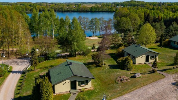 En fastighet vid sjön med två stugor, en grusväg och utsikt över sjön.