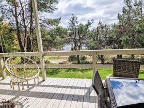 A wooden deck with a white railing, a wicker chair, and a wicker table.