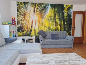 A living room with a grey sofa, a white coffee table, and a bookshelf with toys. - Apartment Lusen by Interhome (Frauenau)