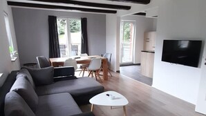 A modern living room with a dark sofa, a white coffee table, and a TV mounted on the wall. - Mit der Natur im Einklang by Interhome (Neuhausen)