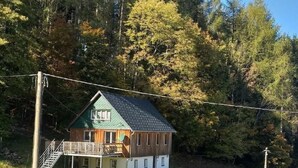 A two-story wooden cabin with a green roof, a balcony, and a small porch area. - Mit der Natur im Einklang by Interhome (Neuhausen)