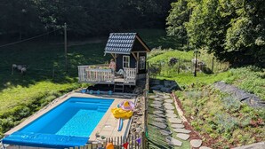 A backyard with a swimming pool, a small wooden house, and a fenced area with stepping stones. - Mit der Natur im Einklang by Interhome (Neuhausen)