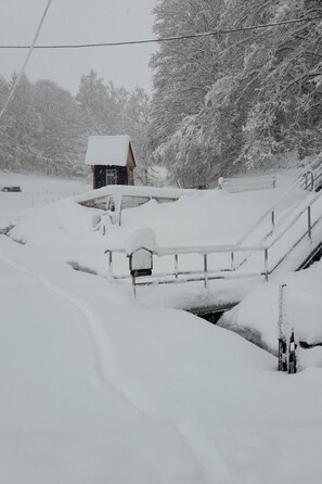 A snow-covered landscape with a small cabin, a wooden bridge, and a fence. - Mit der Natur im Einklang by Interhome (Neuhausen)