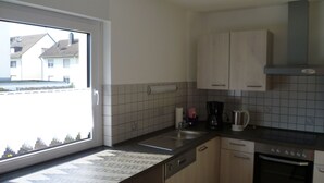 Een moderne keuken met een vaatwasser, oven en een raam met uitzicht op een woonwijk.