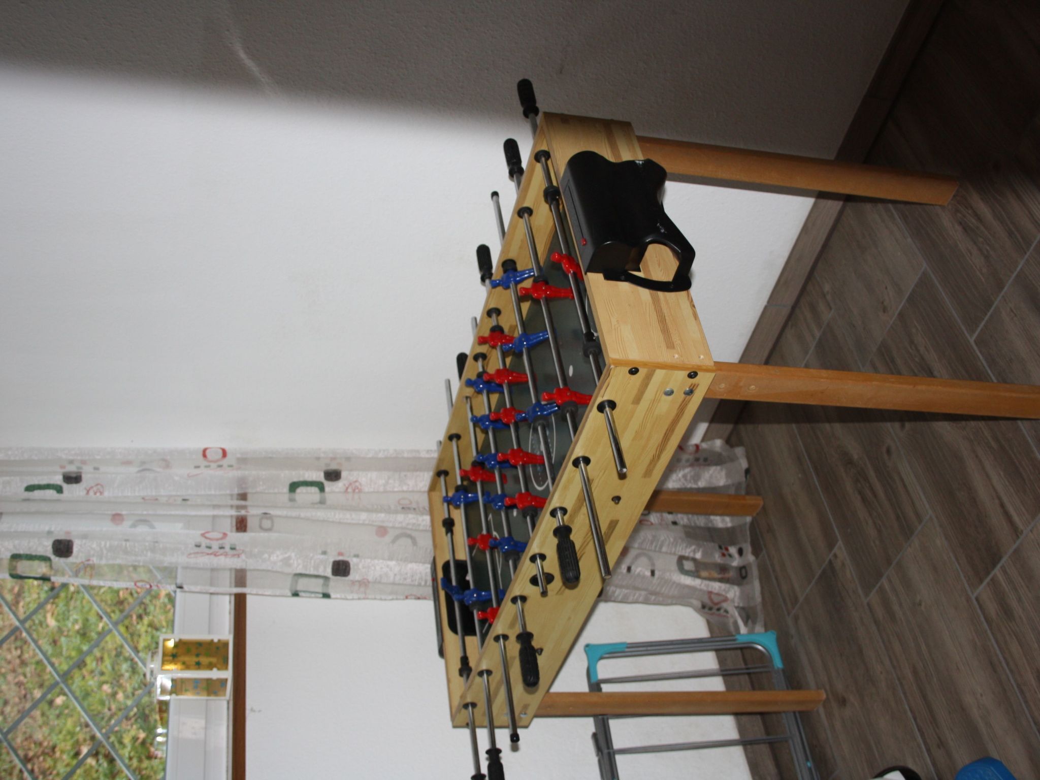 A foosball table in a room with wooden flooring and a white ceiling.