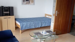 Un espacio habitable compacto con una cama, una mesa de centro de vidrio y dos sofás azules.