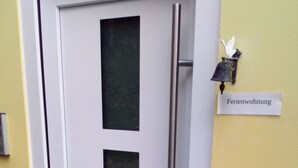 Una puerta con un panel de vidrio esmerilado y un picaporte de metal. Un letrero en la pared dice 'Ferienwohnung'.