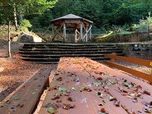 Un porxo de fusta amb un rètol, envoltat d'escales de pedra i un banc de fusta.