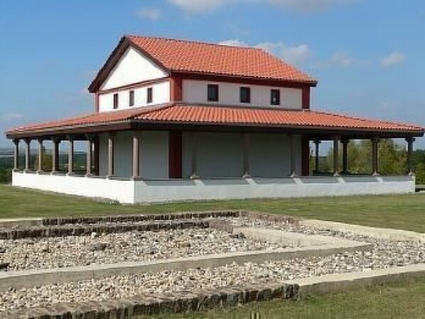 A two-story building with a red-tiled roof and a covered porch.