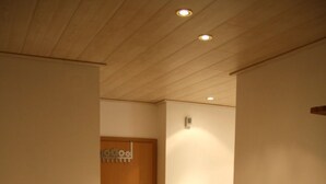 A hallway with a wooden cabinet, a wooden door, and a light switch on the wall. - Trappen by Interhome (Birresborn)