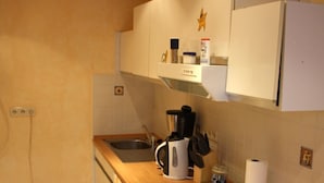 A compact kitchen with a wooden countertop, a built-in oven, a coffee maker, and a kettle. - Trappen by Interhome (Birresborn)