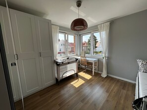 A bright room with a wooden floor, a white desk, a chair, and a bed. - Wohnung in der Próżna-Straße in Kołobrzeg by Interhome (Kolobrzeg)