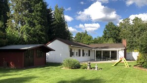 A house with a white exterior, a red garage, and a covered patio area. - Natur pur am Veb´nekoten by Interhome (Niederkrüchten)