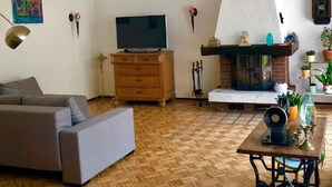 A living room with a sofa, a television, a fireplace, and a table with decorative items. - Natur pur am Veb´nekoten by Interhome (Niederkrüchten)