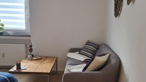 A small, modern living room with a grey sofa, a wooden coffee table, and a window with blinds. - Zentrale, liebevoll eingerichtete Ferienwohnung by Interhome (Monheim)