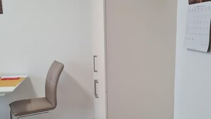 A room with a beige wardrobe, a desk with a chair, a trash bin, and a calendar on the wall. - Zentrale, liebevoll eingerichtete Ferienwohnung by Interhome (Monheim)