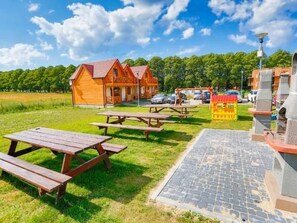 Un rustico chalet in legno con tavoli da picnic e un'area barbecue.
