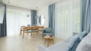 A modern living room with a dining area, featuring a sofa, a coffee table, and a dining table with chairs. - Wohnung für 6 Personen "Nowe Miedzywodzie" by Interhome (Miedzywodzie)