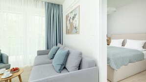 A modern, well-lit room with a grey sofa, a bed with a light blue blanket, and a small wooden table with cups and a basket of fruit. - Wohnung für 6 Personen "Nowe Miedzywodzie" by Interhome (Miedzywodzie)
