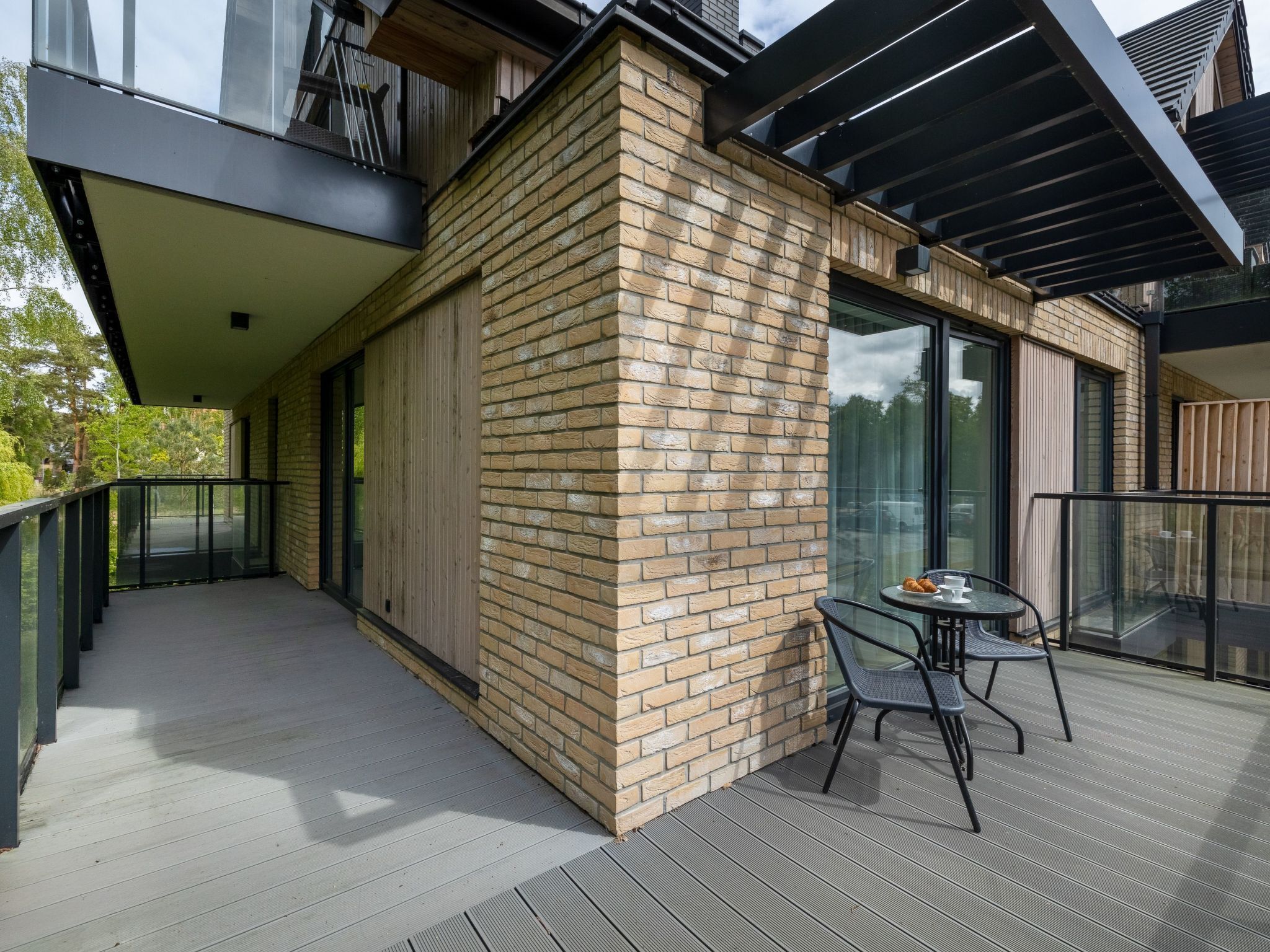 Un bâtiment moderne avec une façade en briques, de grandes fenêtres et un balcon doté de sièges pour l’extérieur.