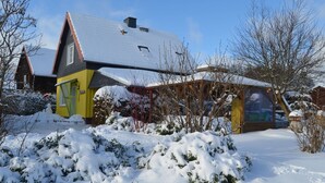 A house with a sloped roof covered in snow, a yellow door, and a green window. - Apartment Dorle by Interhome (Benneckenstein)