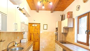 A kitchen with wooden cabinets, a double sink, and a tiled floor.