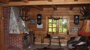 Interior rústico de una cabaña con chimenea de piedra, paredes de madera y cuernos de ciervo colgados en la pared.