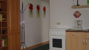 A kitchen with wooden cabinets, a white stove, a coffee maker, and a green mat on the floor.
