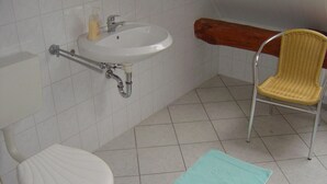 A bathroom with a white sink, a white toilet, and a wicker chair.