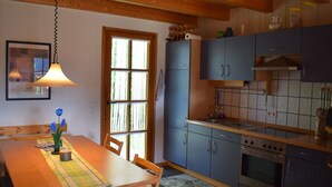Cuina amb armaris de fusta, un fogó i una finestra amb vista a arbres.