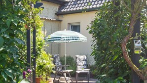 Un espace patio avec deux chaises, un parasol à rayures et des plantes en pot.