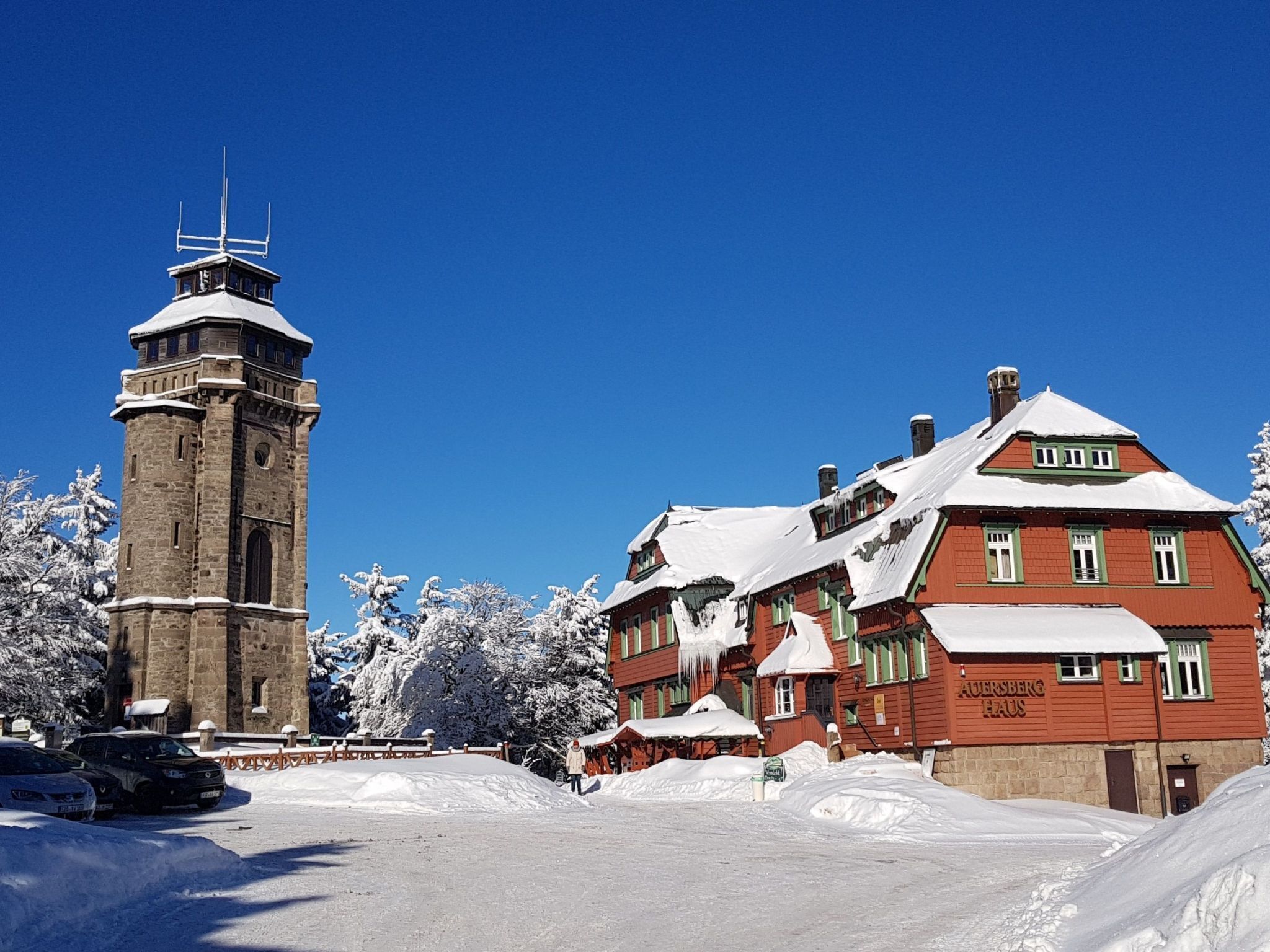 Un edificio histórico con una torre y fachada roja, rodeado de nieve.