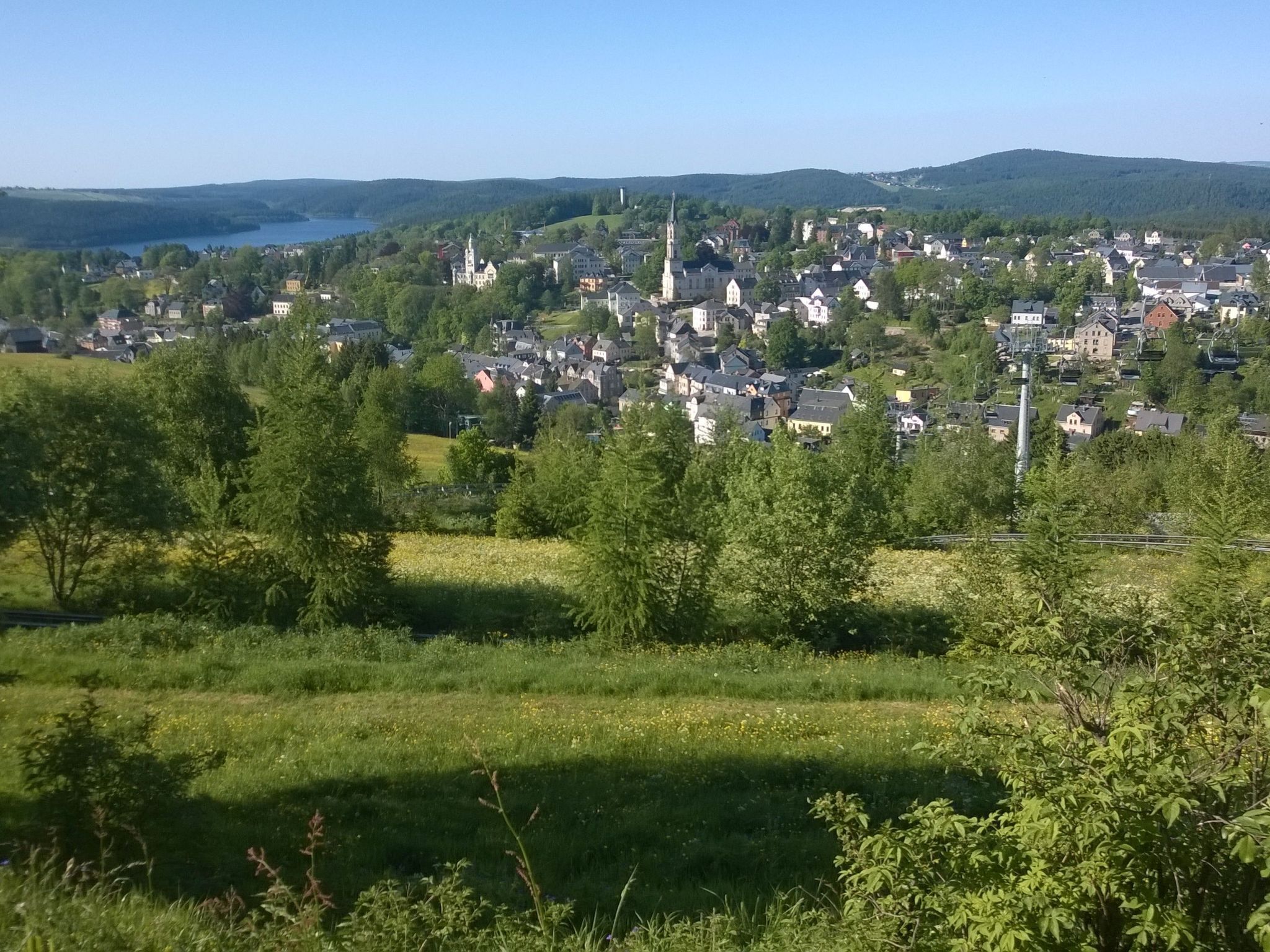 A town with a prominent church spire, surrounded by residential buildings and greenery.