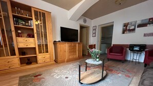 Una sala de estar con un aparador de madera, un televisor de pantalla plana, una mesa de centro de vidrio y un sofá rojo.