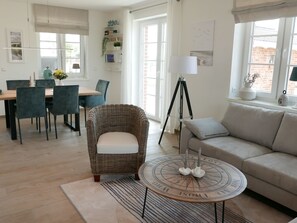 A well-lit living room with a dining area, a wicker chair, a round coffee table with candles, and a sofa. - Vacation home Jette by Interhome (Groß Schoritz)