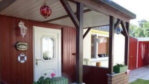 A covered outdoor area with a brick wall, a white door, and a red lantern. - Vacation home Silvia by Interhome (Altwarp)