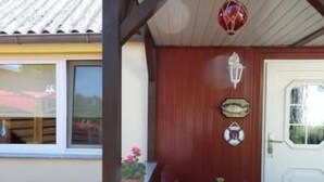 A wooden door with a white window, a small potted plant, and a green fence. - Vacation home Silvia by Interhome (Altwarp)