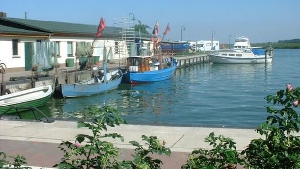 A marina with several boats docked, a building with a green roof, and a clear blue sky. - Vacation home Silvia by Interhome (Altwarp)