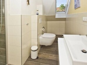Kylpyhuone, jossa on wc, roskakori ja kylpyamme.