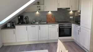 A modern kitchen with white cabinets, a built-in oven, and a coffee maker. - Apartment Möwe by Interhome (Baabe)