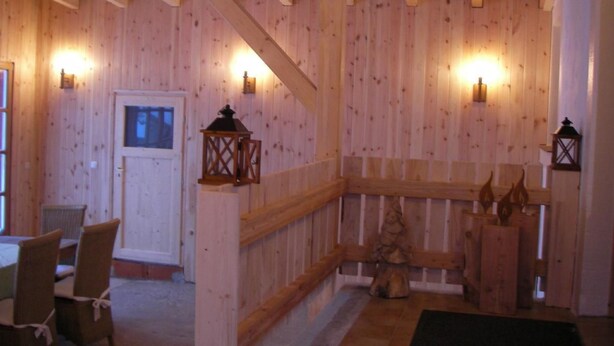 A wooden interior with a wooden bench, a door, and wall-mounted lanterns.