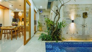 A modern kitchen with wooden cabinets, a dining table with chairs, and a built-in oven. - 3-bedroom Private pool villa City Sanur (Denpasar)
